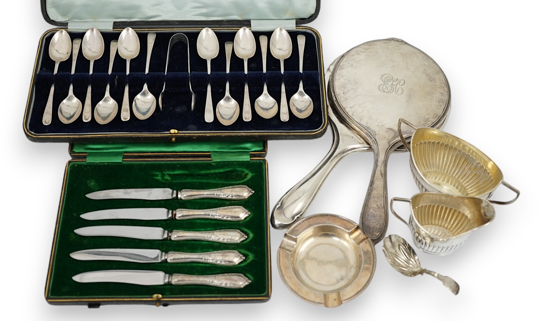 A cased set of twelve George V silver teaspoons with sugar tongs, Sheffield, 1912, two silver hand mirrors, a silver sugar bowl and cream jug, a silver ashtray, a George III silver caddy spoon and cased plated tea knives